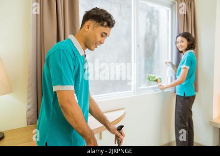 deux femmes de ménage dans la fenêtre et le sol de nettoyage uniforme turquoise Banque D'Images