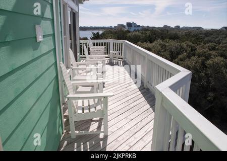 Les chaises longues sont assises sur la terrasse avant d'une maison dans les rives extérieures en préparation pour le coucher du soleil à venir Banque D'Images