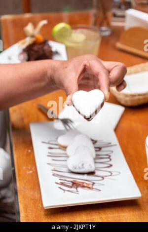 Photo sélective d'une main tenant une pâtisserie en forme de cœur servie dans un restaurant Banque D'Images