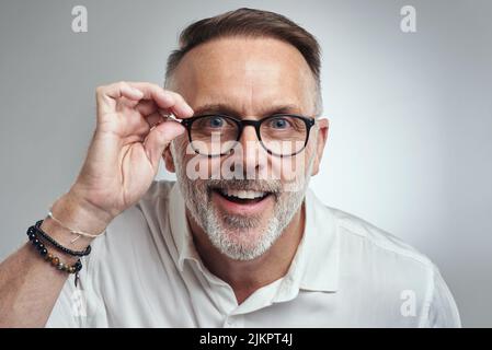 Voir, c'est croire. Portrait studio d'un homme mature portant des lunettes sur fond gris. Banque D'Images