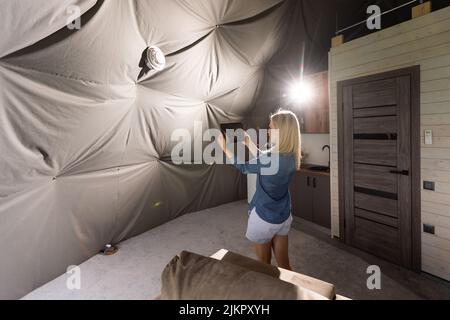 femme avec une tablette qui active le système de ventilation comme récupérateur pour la qualité de l'air frais à l'intérieur, maison intelligente Banque D'Images