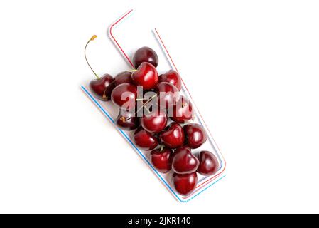 Plat de cocktail de cerise créatif à base de cerises douces et de pailles à boire isolées sur fond blanc avec espace de copie. Banque D'Images