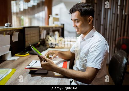 vue latérale de la réceptionniste à l'aide du bloc-notes de la réception de l'hôtel Banque D'Images