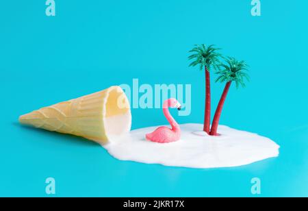 Figurine rose flamant dans une flaque de glace à cône gaufré avec palmiers isolés sur fond bleu. Concept de vacances d'été créatif. Banque D'Images