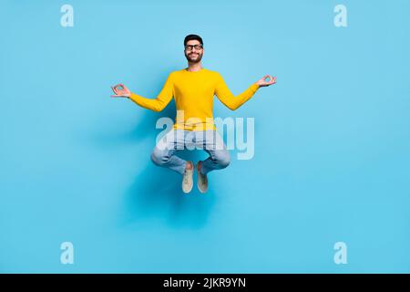 Photo pleine grandeur de l'insouciance positif gars saut méditer les yeux fermés isolés sur fond bleu de couleur Banque D'Images