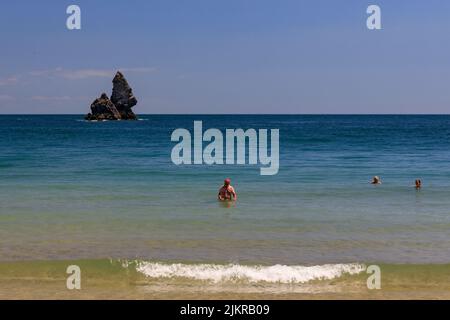 Nageurs à la plage de Broadhaven avec Church Rock Beyond, Pembrokeshire, pays de Galles, Royaume-Uni Banque D'Images