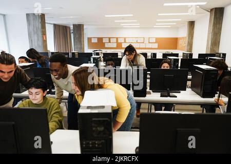 Jeunes élèves multiraciaux utilisant des ordinateurs pendant la classe d'affaires à l'école - accent sur le visage des enseignants Banque D'Images