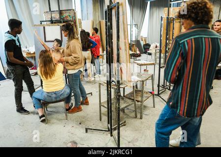 Professeur mature travaillant avec des élèves de l'art pendant la classe de peinture à l'école - Focus sur le visage de l'enseignant Banque D'Images