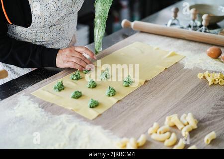 Femme prépare des raviolis frais à l'intérieur de l'usine de pâtes Banque D'Images