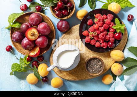Ingrédients pour un smoothie sain. Lait et baies (framboise, cerise, prune, abricot) sur une table en pierre. Alimentation saine, alimentation crue et végétalien f Banque D'Images