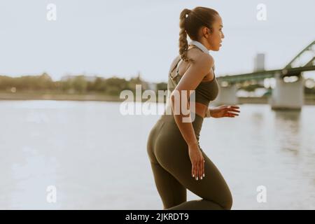 Les jeunes actifs à la belle femme d'exécution sur la promenade le long de la rivière Banque D'Images