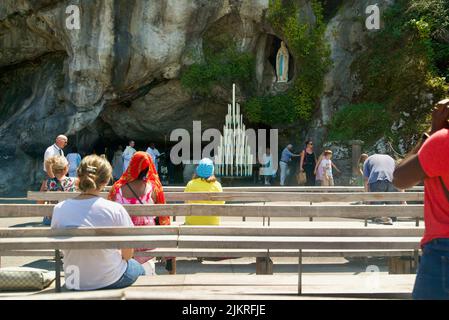 Personnes rassemblées à la Grotte de Massabielle/Grotte des apparitions au Sanctuaire de notre-Dame de Lourdes, pèlerinage à Lourdes personnes dans la grotte Banque D'Images