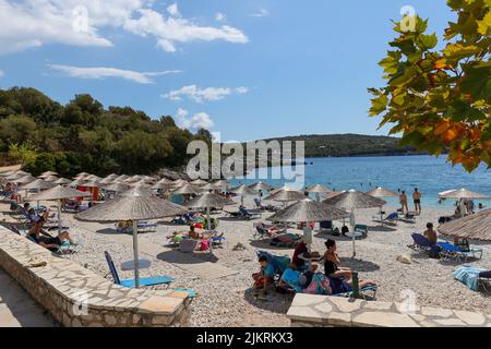 Touristes se relaxant sur des chaises longues sur l'idillique plage d'Ammoussa sur l'île de Lefkada, Grèce. Une destination estivale grecque parfaite. Banque D'Images