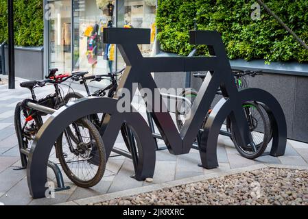 Support de vélo intéressant en forme de grand vélo avec de nombreux vélos garés à lui dans un emplacement urbain de shopping. Banque D'Images