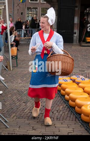 une belle dame en costume traditionnel avec un panier rempli de fromage au marché aux fromages d'alkmaar Banque D'Images