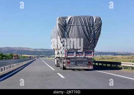 Chariot avec une charge excessive sur la route. Vue arrière. Jour d'été ensoleillé sur l'asphalte. Banque D'Images