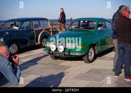 An automotive enthusiast takes photo of classic green SAAB 96 V4 Rally from 1970s at the Bray Vintage Car Club show. An open air retro cars display. Stock Photo