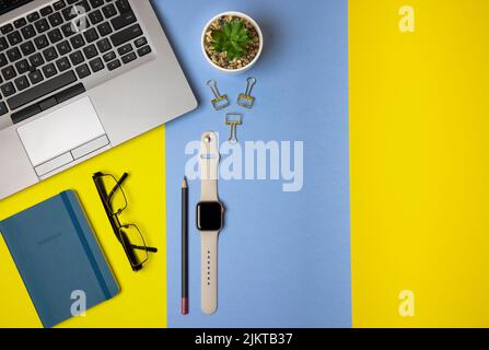 Un bureau à plat avec ordinateur portable, ordinateur portable, montres intelligentes et matériel de bureau Banque D'Images