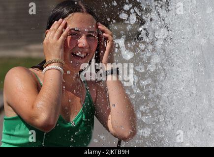 Berlin, Allemagne. 03rd août 2022. Une jeune femme ukrainienne profite de l'été dans la capitale allemande et se rafraîchit à des températures d'environ 35 degrés Celsius dans une fontaine de la ville dans le quartier de Mitte. Selon les météorologues, les températures continueront d'augmenter dans les jours à venir. Credit: Wolfgang Kumm/dpa/Alay Live News Banque D'Images