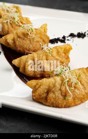 A vertical shot of tasty fried dumplings on a white plate Banque D'Images