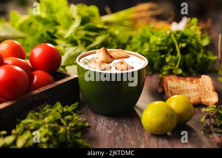 Un gros plan d'une soupe de tomates avec des morceaux de pain dans elle rempli dans un grand bol sur une table en bois Banque D'Images