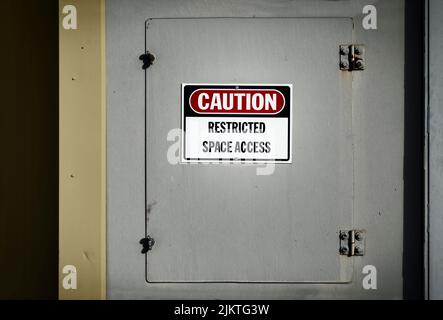 A view of a confined space locked off access door with a 'restricted space access' notice on it Stock Photo