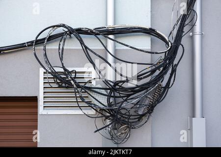 Câbles électriques enchevêtrés et désordonnés sur le mur du bâtiment Banque D'Images