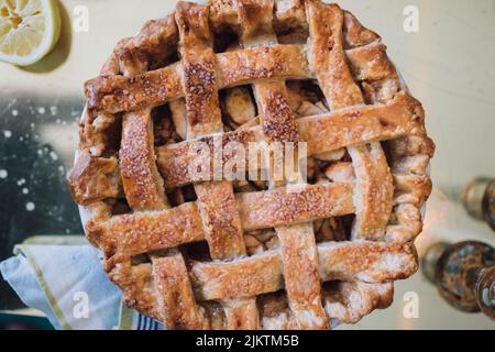 tarte aux pommes à la croûte de treillis cuite encore vie sur la table avec du citron, un torchon, des bougies vertes Banque D'Images