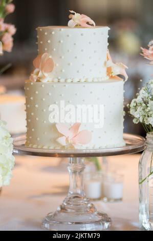 A vertical closeup of a two-tier polka dot wedding cake with flowers. Shallow focus. Stock Photo