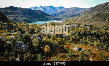 A view of a mountainous area in spring with bushes and stones on the foreground and a lake in distance Banque D'Images