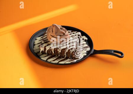 A brownie with melted dark and white chocolate and an ice cream on top Banque D'Images