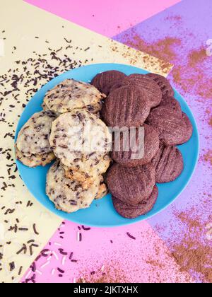 A top view of two kinds of sweet cookies with chocolate and white cream on a blue plate Stock Photo