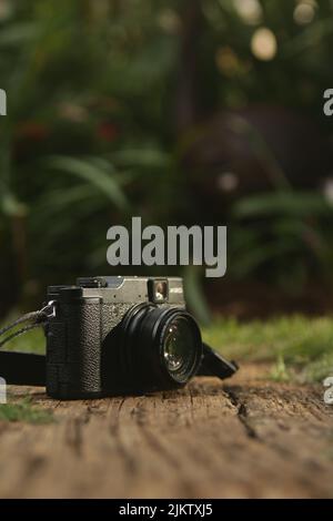 A selective shot of a vintage-style digital camera on the ground over blurred nature back Stock Photo