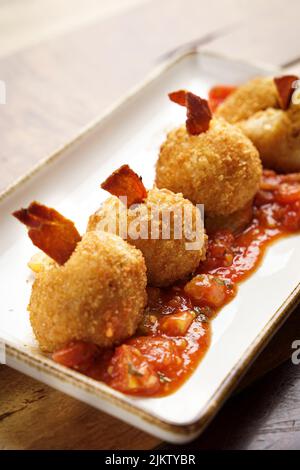 A closeup shot of a Sausage Croquettes with sauce on a white plate Stock Photo