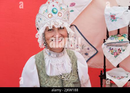 Portrait d'une femme âgée souriante dans une ancienne coiffure russe stylisée - kokoshnik en vacances rurales. Banque D'Images