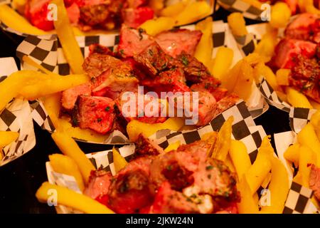 Meat with french fries on a paper bowl at the Boqueria market in Barcelona (Spain). Banque D'Images