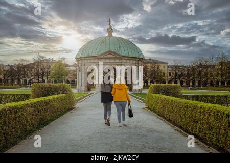 Deux jeunes amis se promènent dans Hofgarten, parc du centre-ville de Munich. Magnifique coucher de soleil épique en arrière-plan du parc de la ville Banque D'Images