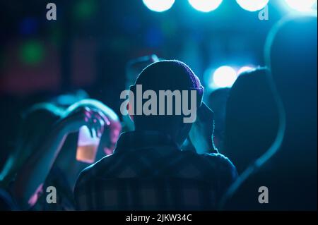 A back view of a young man in a hat in a club with blue lights Banque D'Images