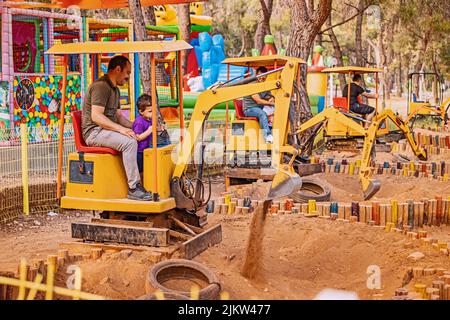 12 juin 2022, Antalya, Turquie : les pères avec enfants conduisent des excavateurs de jouets dans un parc d'attractions Banque D'Images