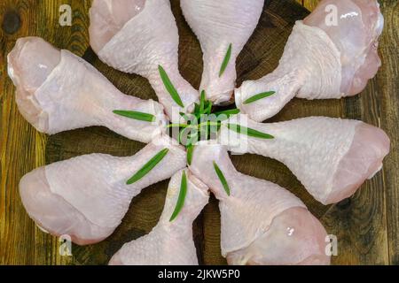 Pilons de poulet frais crus avec brindilles au romarin. Cuisine sur la cuisine. Mise au point sélective. Gros plan. Banque D'Images