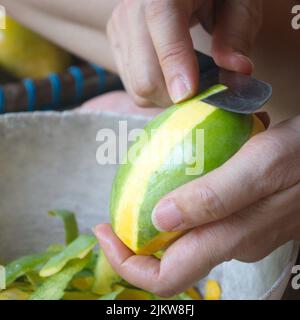 Femme main à l'aide d'un couteau pour peler la mangue mûre. Les fruits locaux sont doux. Banque D'Images