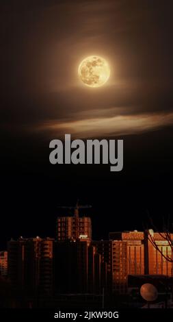 A mesmerizing view of a moon in the dark sky at night over a city Stock Photo