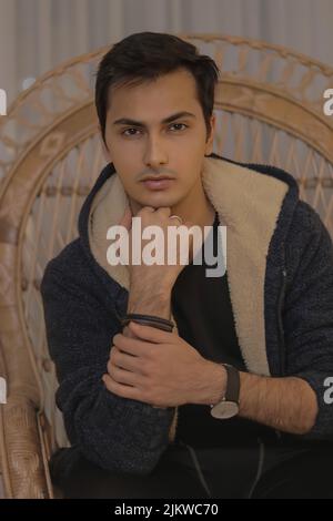 Portrait vertical d'un homme posant, portant une veste et une montre-bracelet et regardant l'appareil photo Banque D'Images