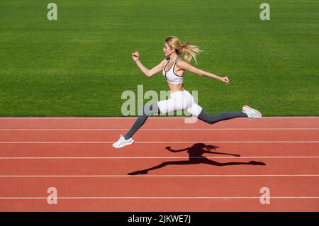 Femme en train de courir pendant. Arrière-plans sportifs. Coureur. Professionnel sportswoman pendant la séance d'entraînement à la course. Femme qui court sur le circuit du stade Banque D'Images