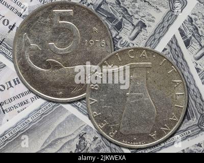 A vintage Italian lira coin from 1976 isolated on a paper money background Stock Photo