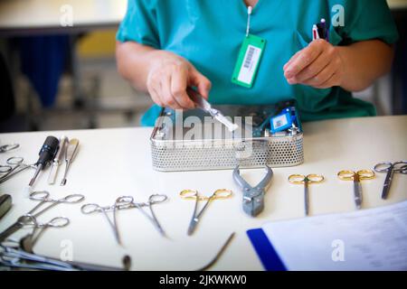 Avant la stérilisation des instruments chirurgicaux, un assistant médical recompose les boîtes d'instruments utilisées dans la salle d'opération. Banque D'Images