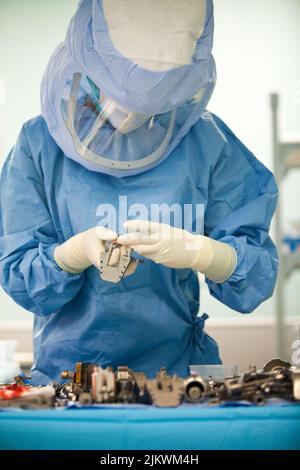 Chirurgie orthopédique, une infirmière prépare les instruments chirurgicaux pour l'installation d'une prothèse de genou. Banque D'Images