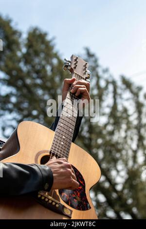 mains jouant de la guitare à l'extérieur en journée avec fond de nature Banque D'Images