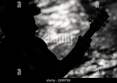 silhouette d'un garçon avec une guitare sur la rive Banque D'Images