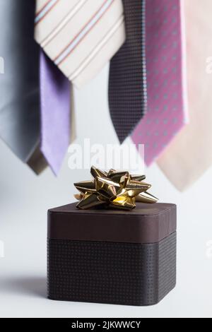 Vertical close up of a brown gift on a white background with colorful ties. Banque D'Images
